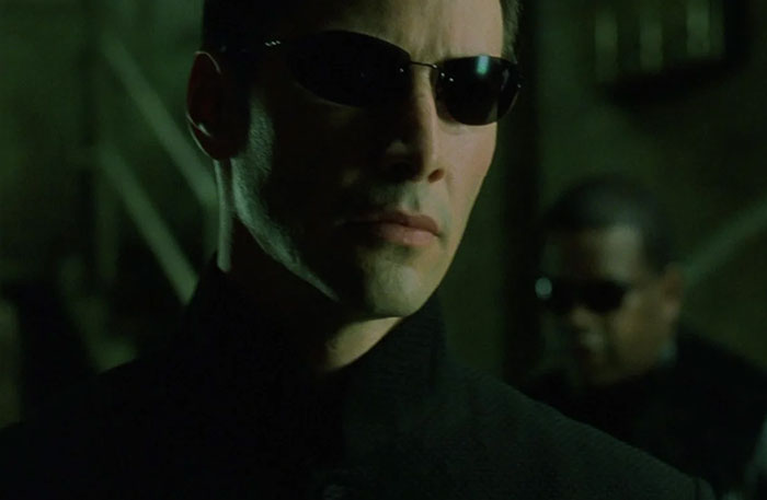 Keanu Reeves wearing suit and glasses