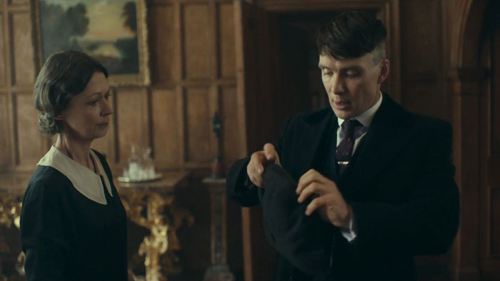 Tommy Shelby putting on a hat
