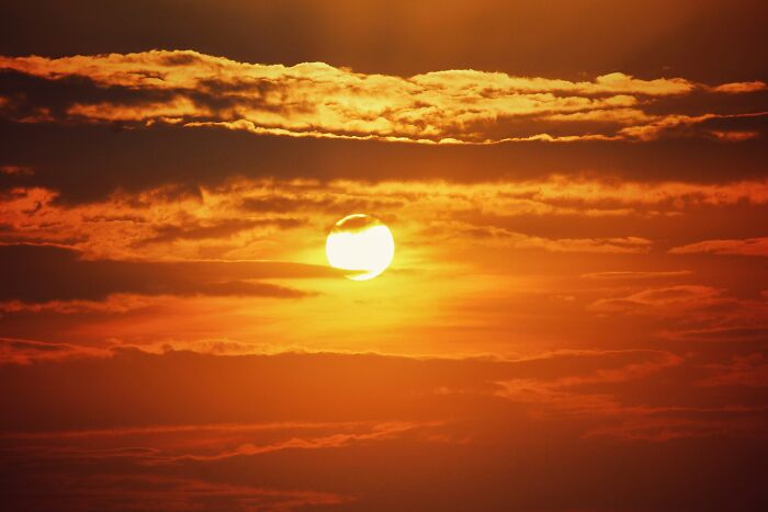 Sun setting behind layered clouds with warm orange and yellow tones illustrating a metaphor for the worst trend topic.
