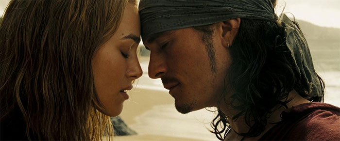 Will and Elizabeth sharing an intimate moment on a beach, featured in Pirates of the Caribbean quotes treasure.