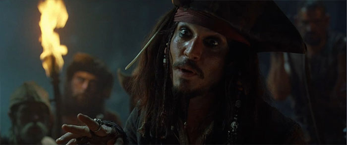 Jack Sparrow speaking in a dimly lit scene featuring Pirates of the Caribbean quotes and sea adventure themes.