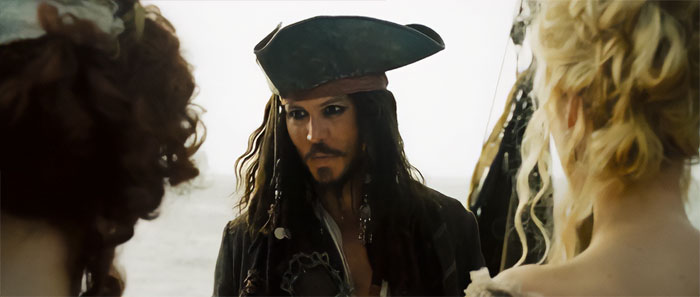 Jack Sparrow in pirate costume talking to two women by the sea, capturing iconic Pirates of the Caribbean quotes scene.
