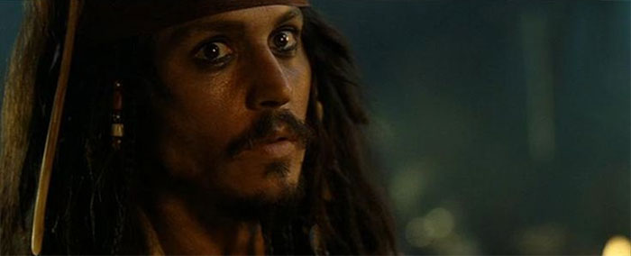 Jack Sparrow looking intensely at someone scared in a dark setting, capturing iconic Pirates of the Caribbean moment.