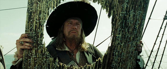 Captain Barbossa examining a broken ship mast, capturing a moment from Pirates of the Caribbean quotes and scenes.