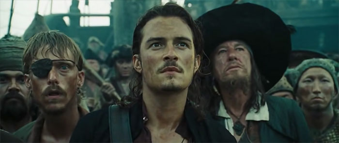 Will looking up with a determined expression among a group of pirates, capturing the spirit of Pirates of the Caribbean quotes.