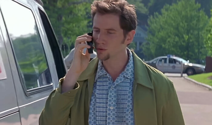 Randy talking to cellphone near a van 