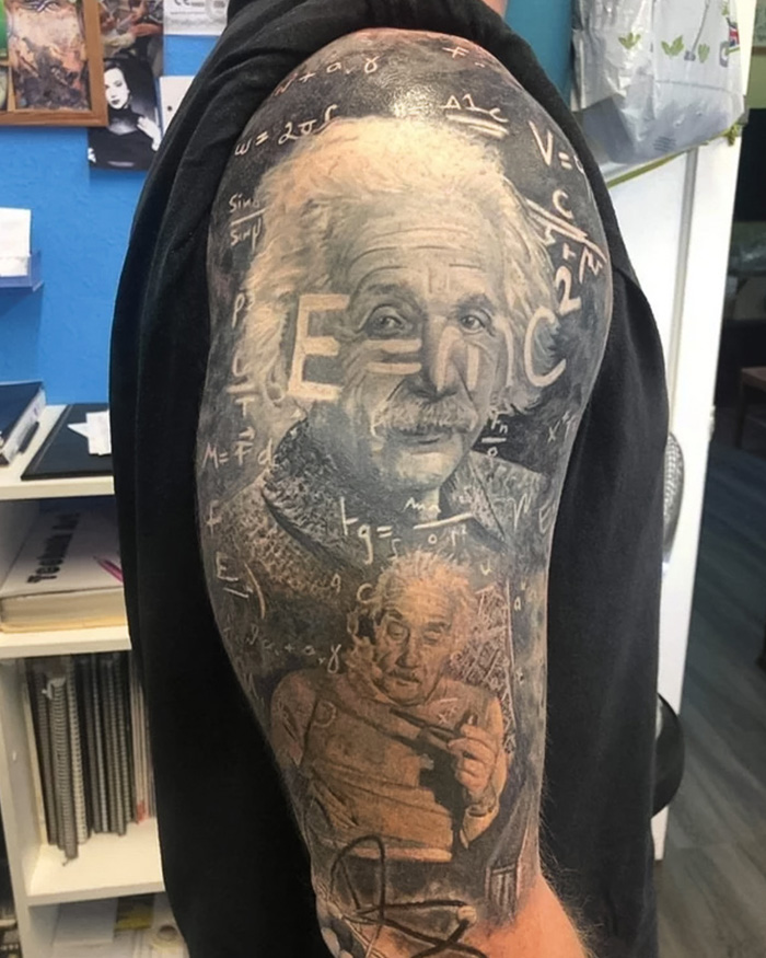 Science tattoo featuring mathematical equations and a famous physicist portrait on a person's upper arm.