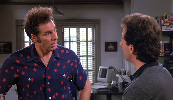 Kramer in a blue shirt animatedly talking to Jerry, showcasing funniest Seinfeld quotes that sum up everyday life.