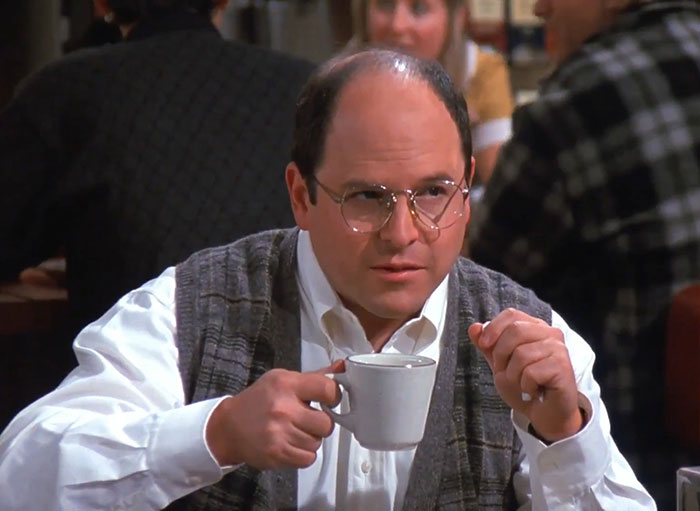 George wearing a white shirt and glasses, holding a coffee cup, representing funniest Seinfeld quotes about everyday life.