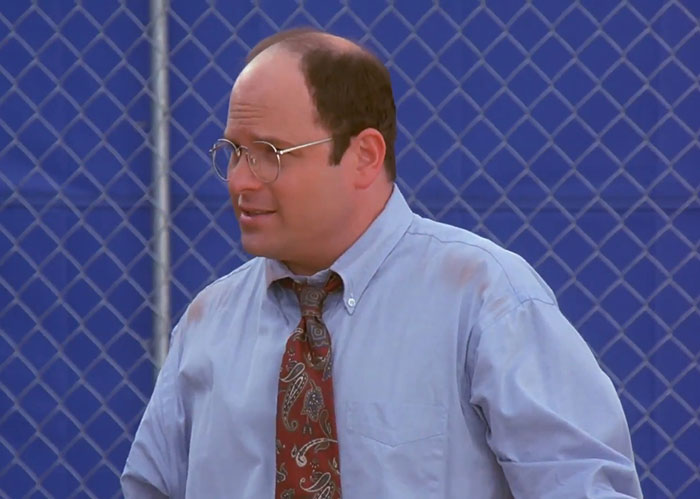 George in a blue shirt and patterned tie, expressing a classic moment from funniest Seinfeld quotes about everyday life.