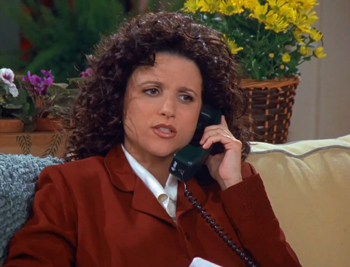 Elaine from Seinfeld in a red suit talking on the phone, capturing funniest Seinfeld quotes about everyday life.