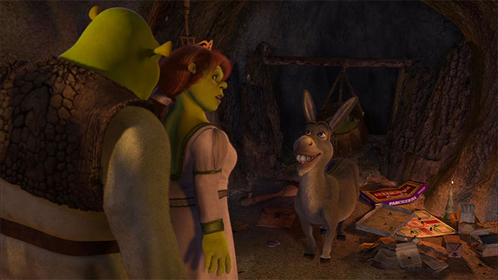 Shrek, Fiona, and Donkey talking inside a dim swamp cave surrounded by scattered games and papers.