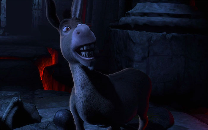 Donkey from Shrek looking scared in a dark swamp setting with rocks and glowing red light in the background.