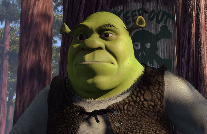 Shrek watching in front of a wooden sign in the swamp, illustrating popular Shrek quotes from the deep swamp.