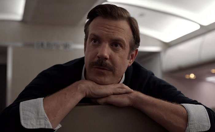 Ted Lasso wearing black sweater and white shirt