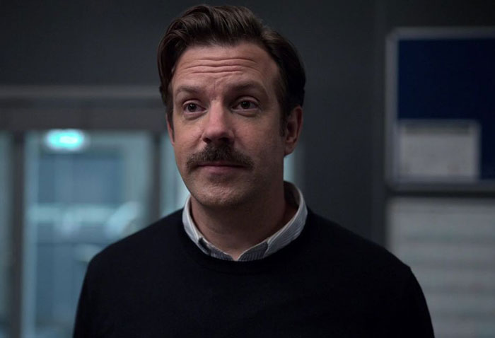 Ted Lasso wearing black sweater and white shirt