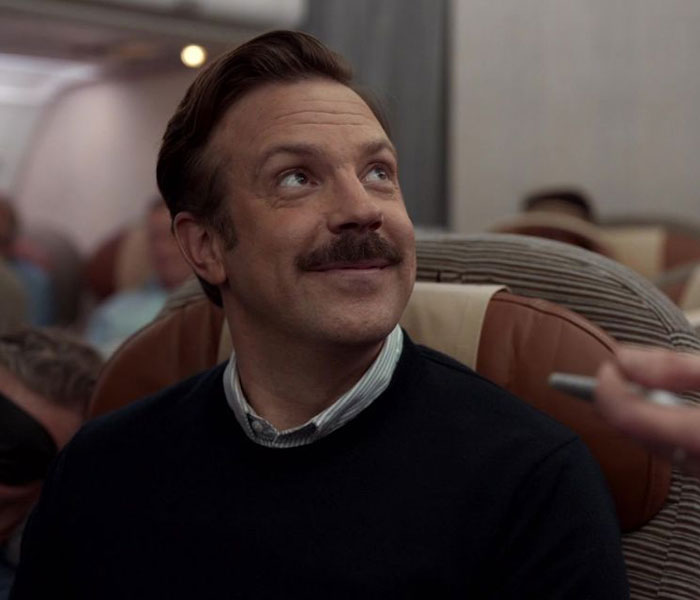 Ted Lasso wearing black sweater and white shirt 