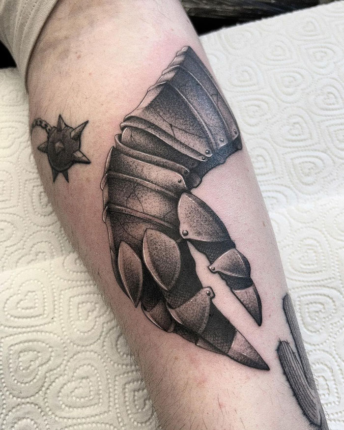 Dark Souls video game tattoo of armored gauntlet and mace on forearm, perfect for hardcore gamers.