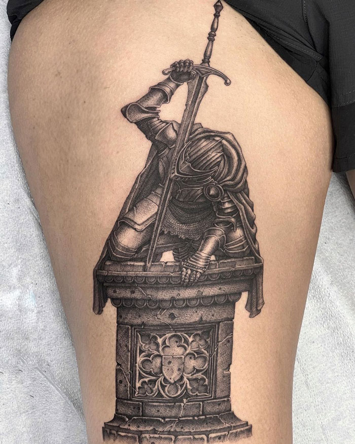 Dark Souls video game tattoo on someone's thigh, depicting a warrior with a sword by a detailed pedestal.