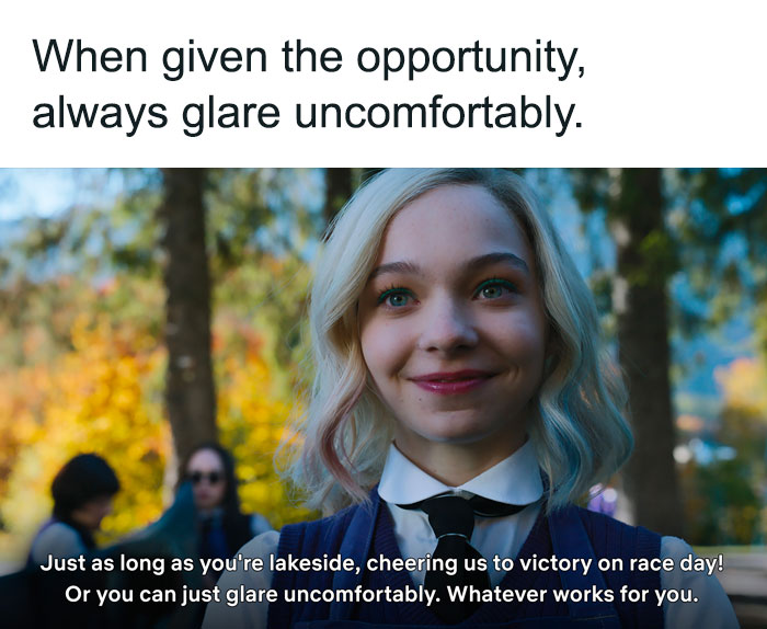 Character from Netflix's Wednesday standing outdoors, smiling, with trees in the background.