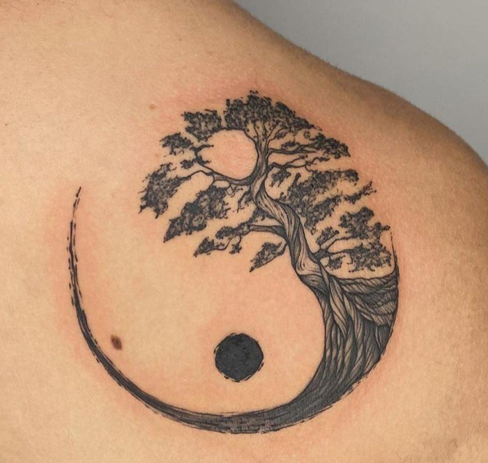 Tree-themed yin yang tattoo on shoulder, symbolizing life duality.