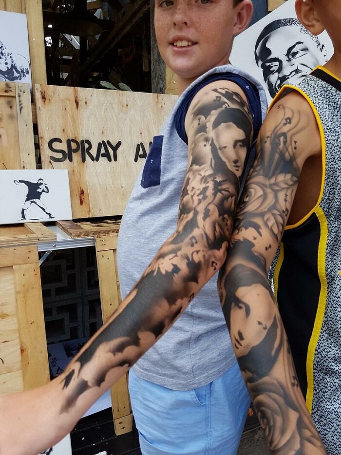 Kids showing off spray-on tattoos with artistic designs on their arms.