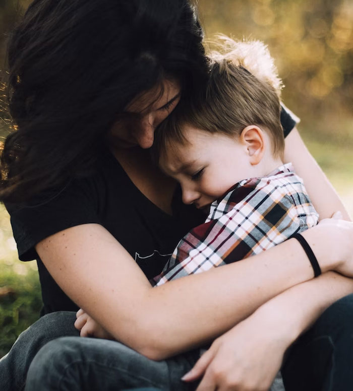 Mother hugging her son outdoors, reflecting on rich grandparents' promise of inheritance and her concerns about it.