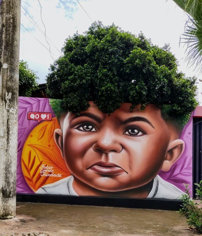 Street Artist Continues To Paint Portraits On Walls Next To Trees That Double As Hair