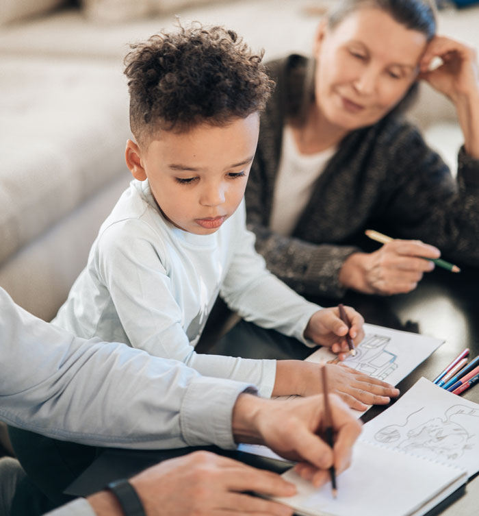 Young boy drawing with grandparents nearby, illustrating rich grandparents promise grandchild inheritance scenario.