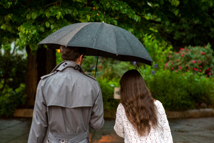 A couple walking under an umbrella in a garden, highlighting relationship and hygiene issues.