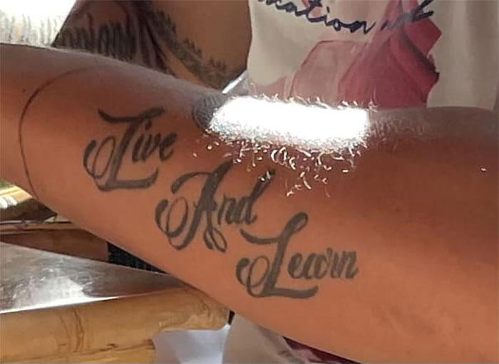 Arm tattoo reads "Live And Learn," where "And" is misspelled, highlighting a permanent tattoo mistake.