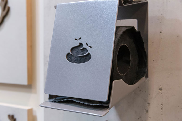 Toilet paper holder with a humorous poop symbol, highlighting hygiene themes.