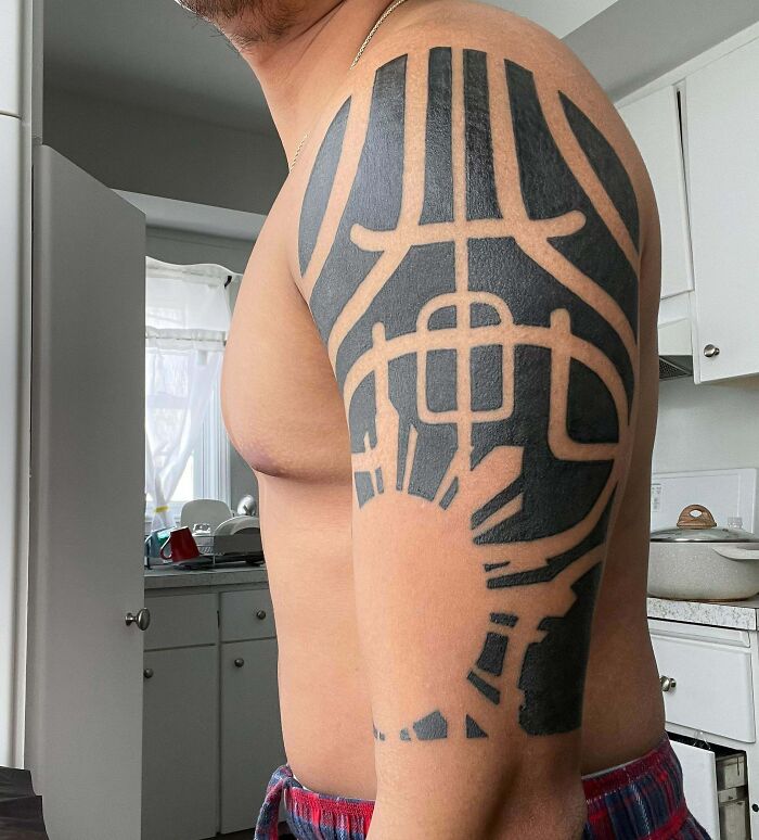 Arm with a tribal tattoo design showing bold black patterns in a kitchen setting.