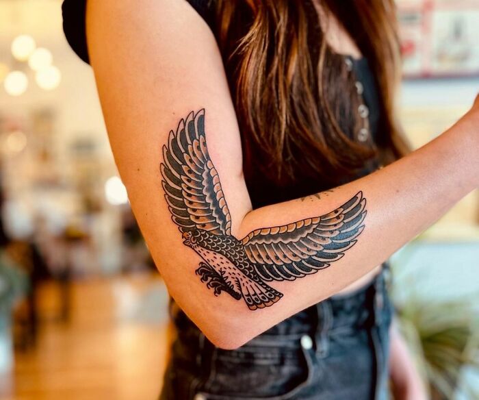 Woman with a detailed eagle tattoo design on her elbow.