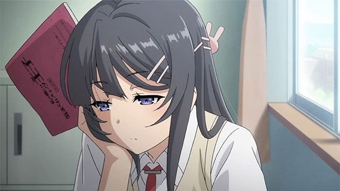 Anime female character sitting by a window, holding a book and appearing thoughtful.