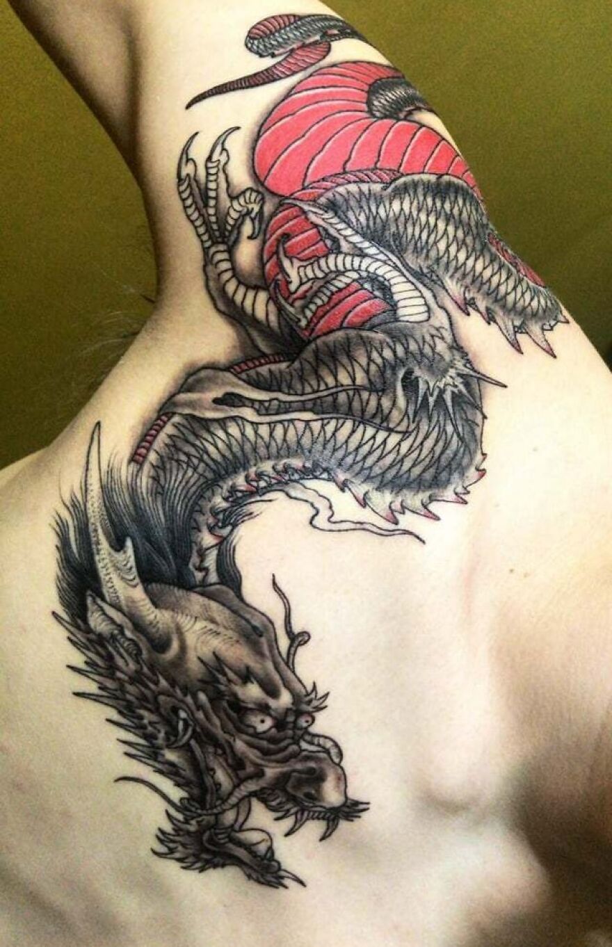 Intricate dragon tattoo design on upper arm, showcasing detailed scales and fierce expression.