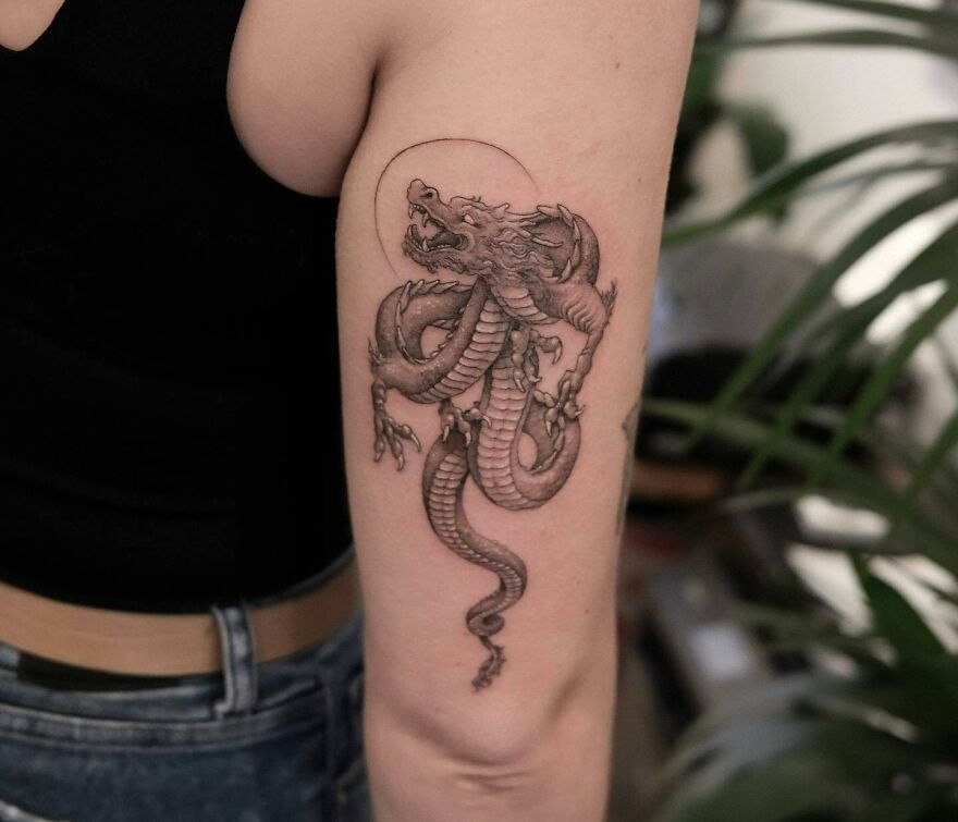 Arm with detailed dragon tattoo, showcasing intricate design elements and textures.