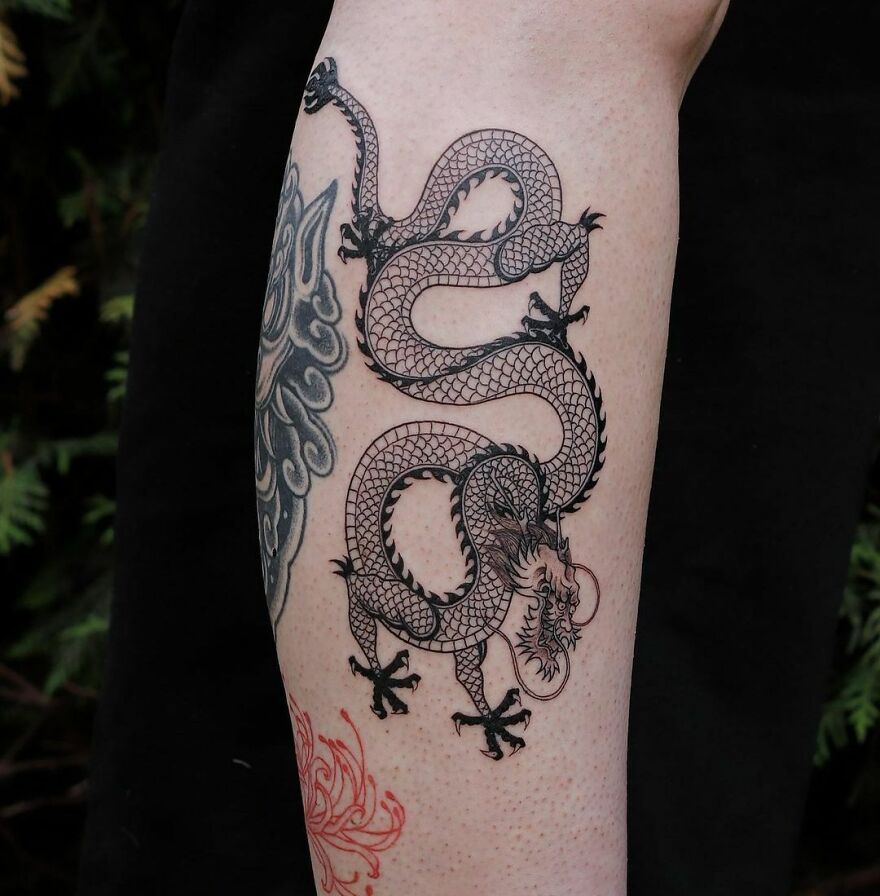 A detailed dragon tattoo design wrapped around an arm in black ink.