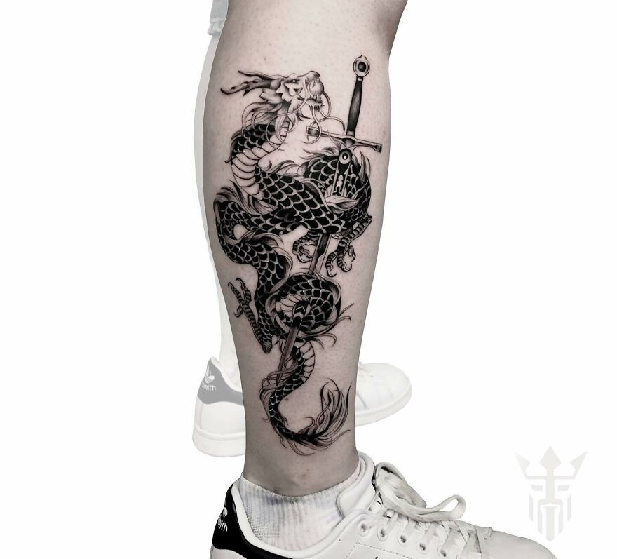 Black dragon tattoo design on a leg with sword detail, showcasing intricate ink work.