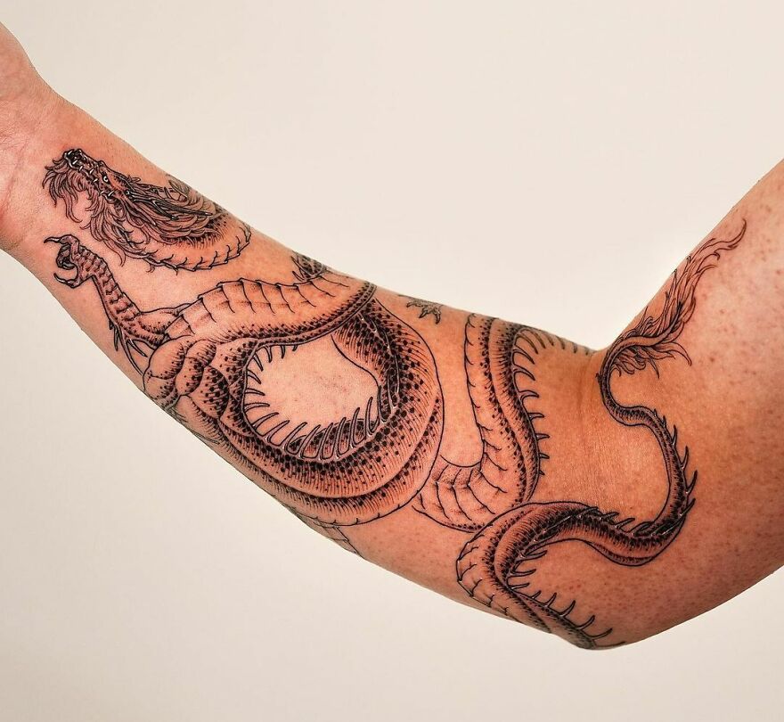 Dragon tattoo design on a person's arm, showcasing intricate details and dynamic curves.