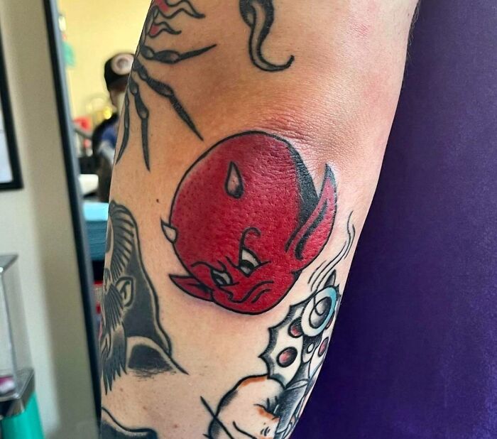 Red devil design on an elbow tattoo, showcasing unique and dazzling tattoo artistry.