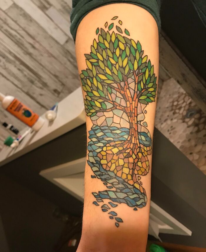 Colorful mosaic-style tree tattoo on forearm, celebrating the wonders of nature.