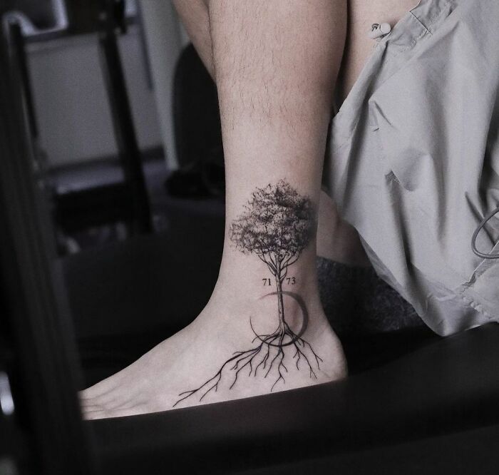 Ankle with a detailed tree tattoo showcasing nature's wonders, emphasizing roots and branches.