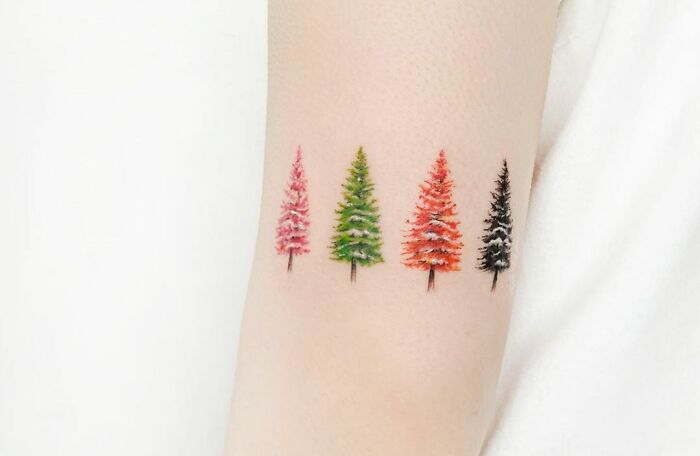 Four colorful tree tattoos on a person's arm, showcasing nature's beauty.