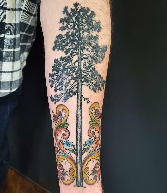 Majestic tree tattoo on forearm with intricate colorful swirls at the base, symbolizing the wonders of nature.