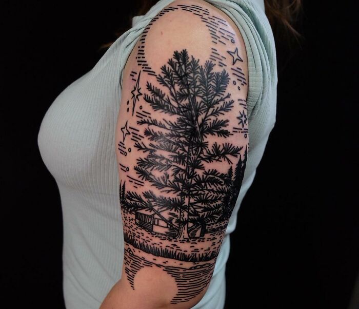 Arm tattoo of a majestic tree with stars, a moon, and a cabin, celebrating the wonders of nature.