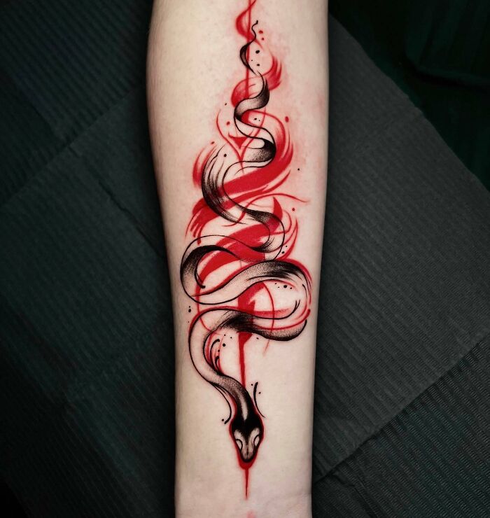 Trash Polka tattoo design of a snake in black and red ink on forearm.