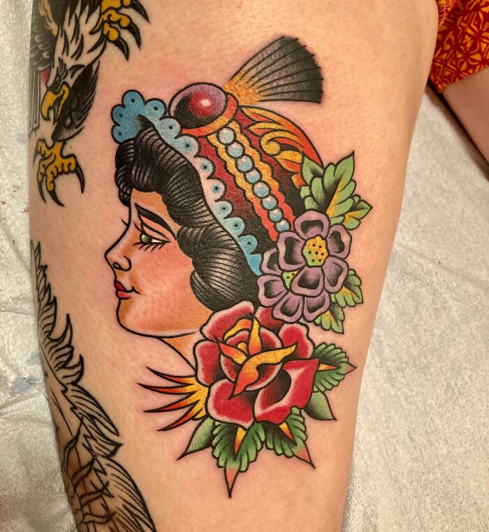 American traditional tattoo featuring colorful flowers and a woman's profile with a detailed headdress.