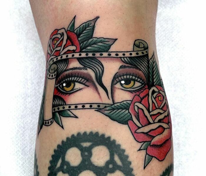 American traditional tattoo with roses and eyes in bold colors on forearm.