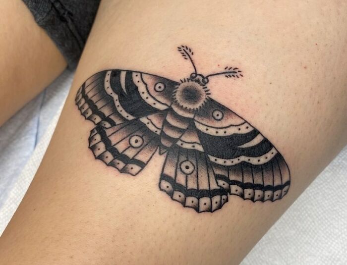 American traditional tattoo design of a detailed black and gray moth on skin.